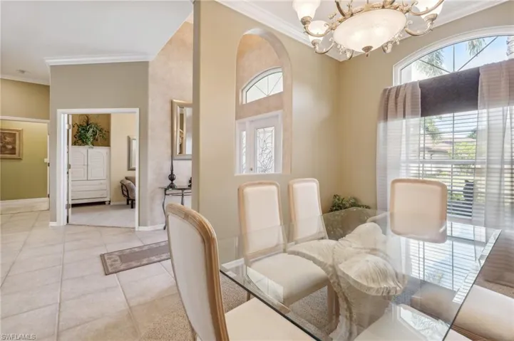 Tiled dining room featuring an inviting chandelier and crown molding