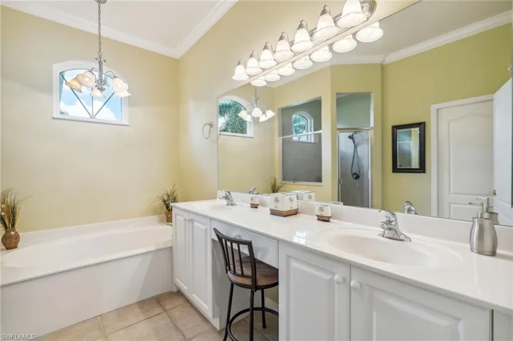Bathroom with vanity, separate shower and tub, ornamental molding, a chandelier, and tile patterned floors