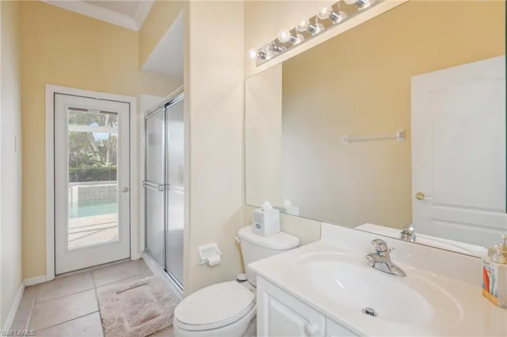 Bathroom with ornamental molding, a shower with shower door, vanity, and toilet