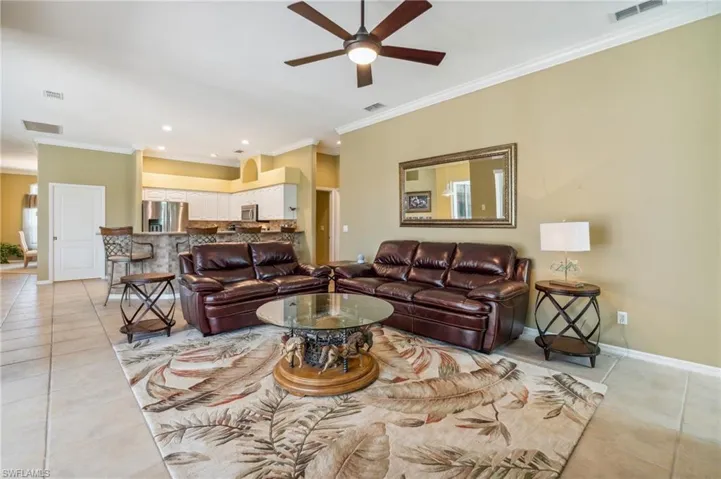 Living room with light tile patterned floors, crown molding, and ceiling fan