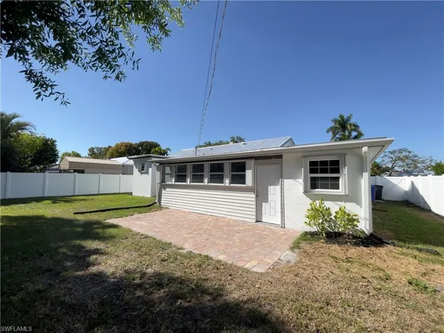 Back of property with a patio area, a fenced backyard, concrete block siding, and a metal roof