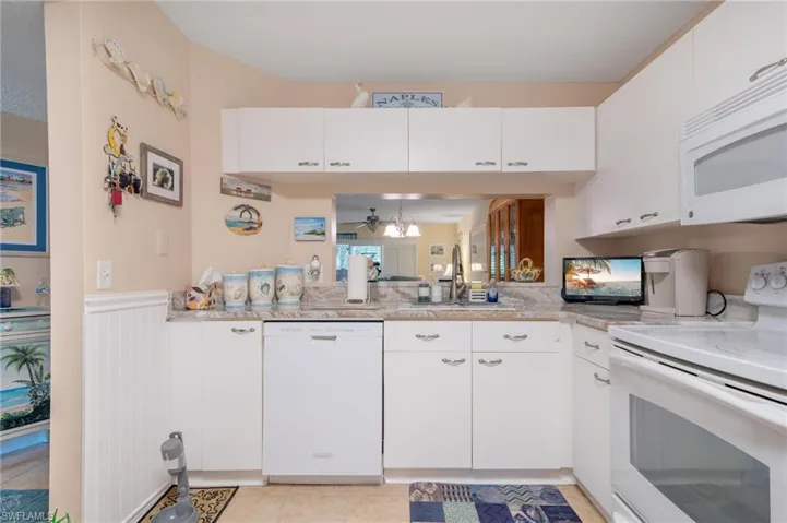 Kitchen featuring white cabinetry, sink, white appliances, ceiling fan, and light tile patterned flooring