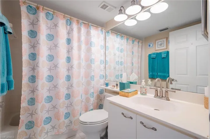 Full bathroom featuring shower / bath combo with shower curtain, vanity, and toilet
