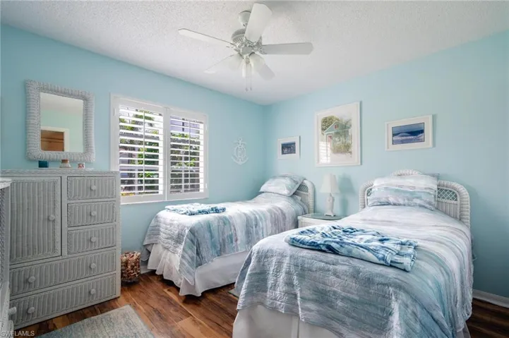Bedroom with ceiling fan, a textured ceiling, and dark wood-type flooring