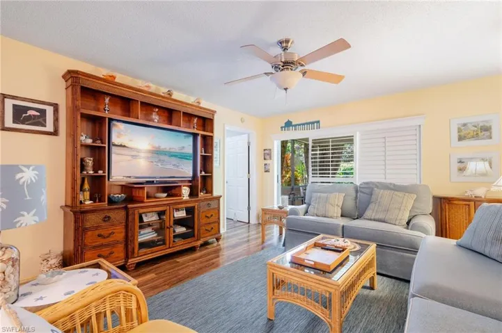 Living room with a textured ceiling, ceiling fan, and wood-type flooring