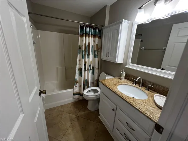 Bathroom featuring vanity, shower / bath combo, and dark tile patterned floors