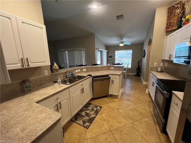 Kitchen featuring white cabinetry, appliances with stainless steel finishes, a ceiling fan, and light tile patterned floors
