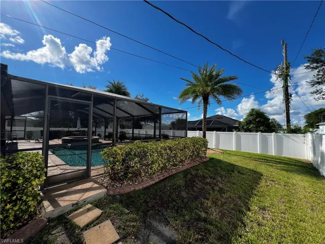 Fenced backyard with glass enclosure, a sunroom, and a pool with connected hot tub