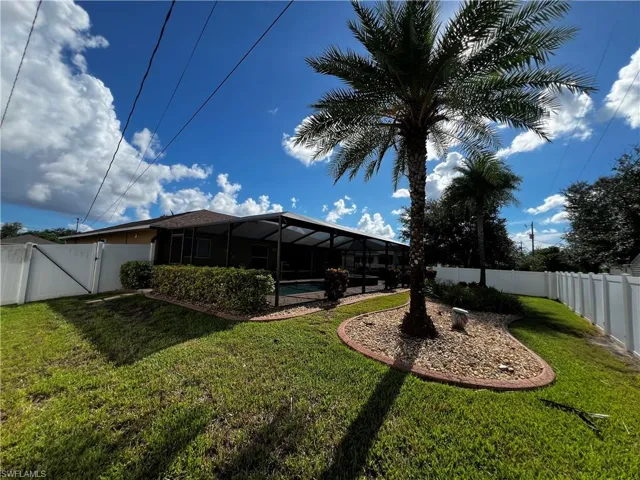 Fenced backyard featuring a gate, a sunroom, glass enclosure, a patio, and an outdoor pool