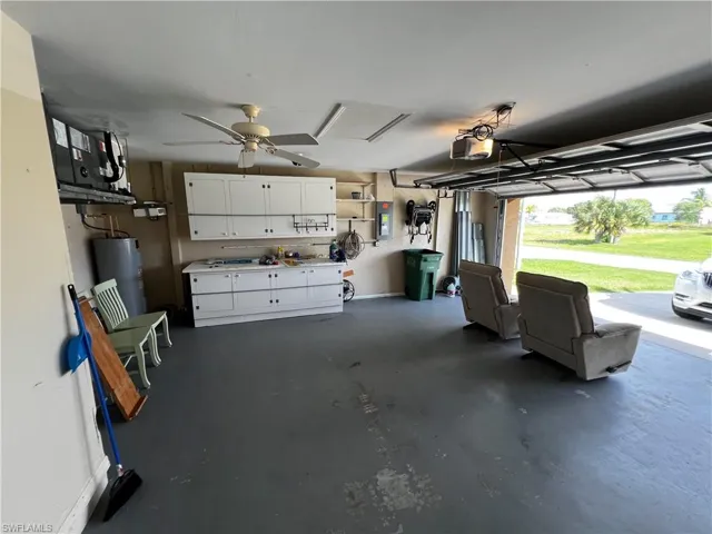 Garage with water heater, electric panel, and a garage door opener