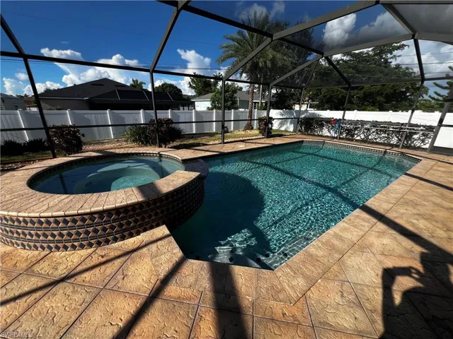 View of swimming pool with a lanai, a sunroom, a pool with connected hot tub, and a fenced backyard