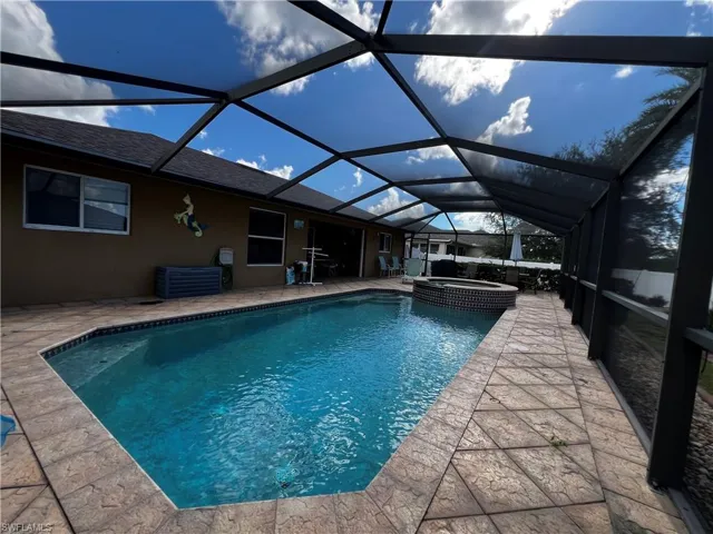 View of pool featuring a sunroom, a lanai, a pool with connected hot tub, and a patio