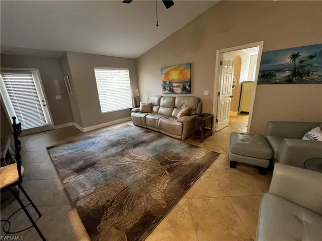 Living area featuring a ceiling fan, arched walkways, light tile patterned floors, and high vaulted ceiling