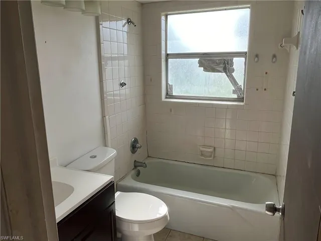 Full bathroom with vanity, tile patterned flooring, tiled shower / bath combo, and toilet