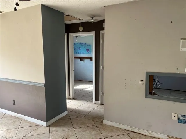 Hall with a textured ceiling and light tile patterned floors