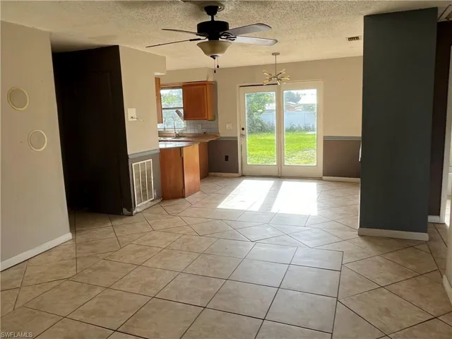 Kitchen featuring ceiling fan with notable chandelier, sink, a textured ceiling, light tile patterned floors, and backsplash