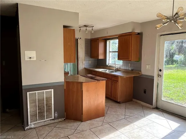 Kitchen featuring rail lighting, tasteful backsplash, sink, and plenty of natural light