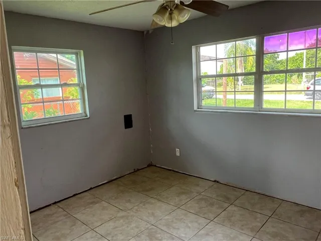Empty room featuring plenty of natural light, ceiling fan, and tile patterned floors