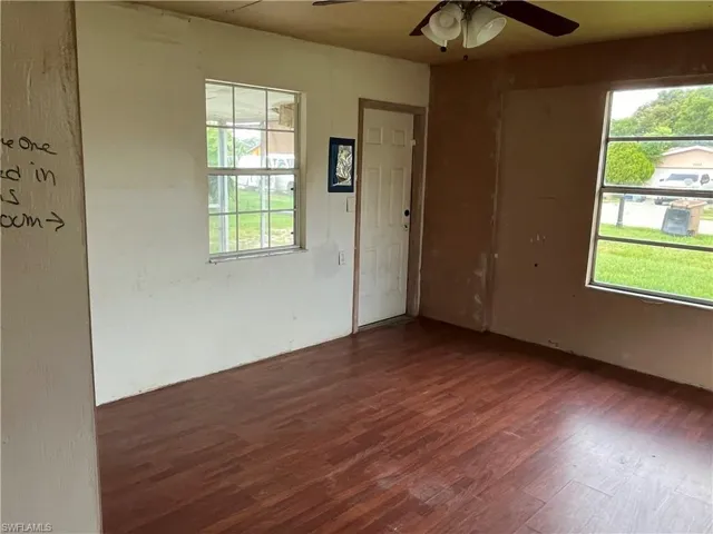 Empty room featuring ceiling fan, wood-type flooring, and a healthy amount of sunlight
