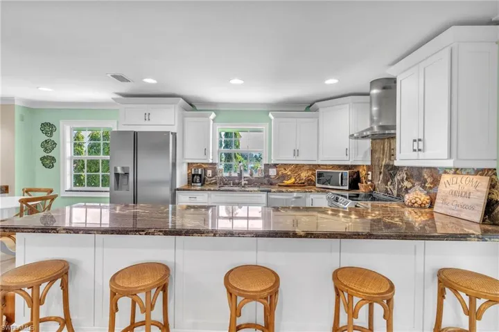 Kitchen featuring a breakfast bar area, a peninsula, stainless steel appliances, dark stone counters, and ornamental molding