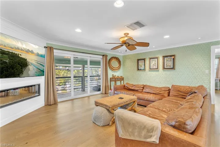 Living room featuring light wood-style floors, wallpapered walls, recessed lighting, ceiling fan, and ornamental molding