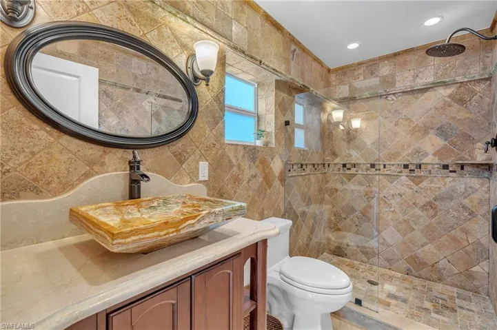 Bathroom featuring vanity, a stall shower, tile walls, and recessed lighting