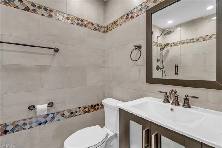 Full bathroom featuring tile walls, vanity, and a tile shower