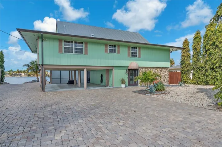 View of front of property featuring a carport, stone siding, driveway, and a patio area