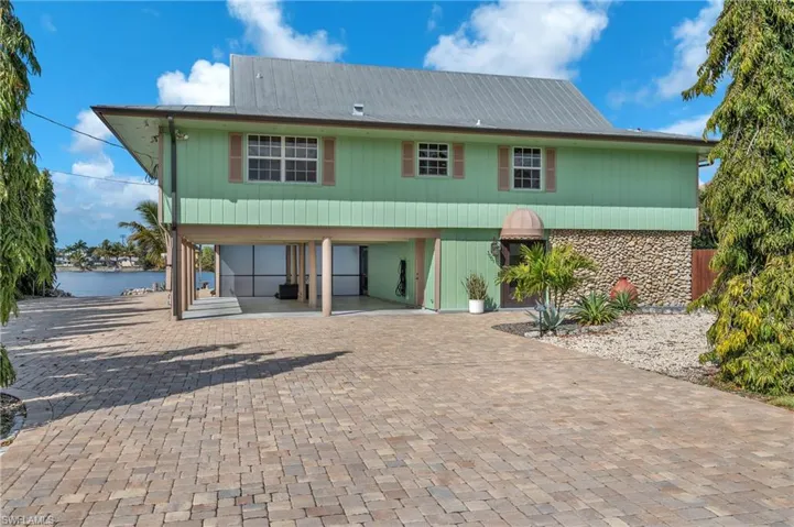 Property featuring a carport, a patio, driveway, and stone siding