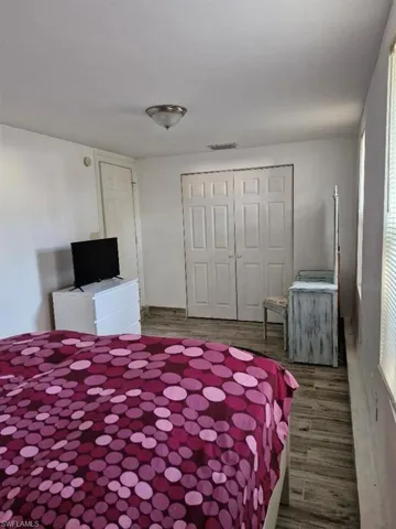 Bedroom, dark wood finished floors, and a closet