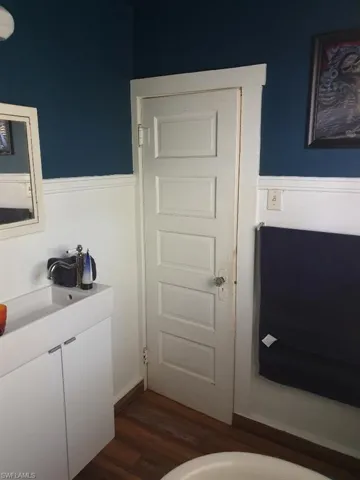 Bathroom with a wainscoted wall, a sink, and wood finished floors