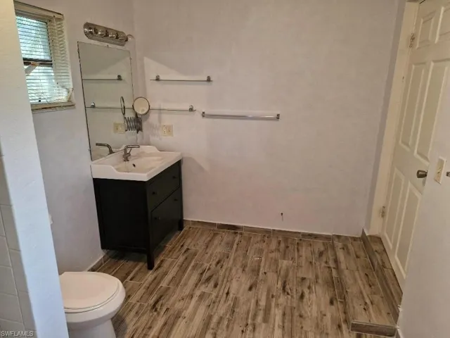 Bathroom with toilet, baseboards, wood finished floors, and vanity