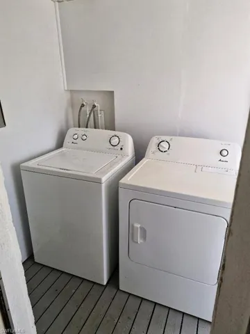 Laundry room with laundry area, washer and clothes dryer, and wood finished floors