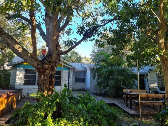 Rear view of house featuring stone siding and a wooden deck