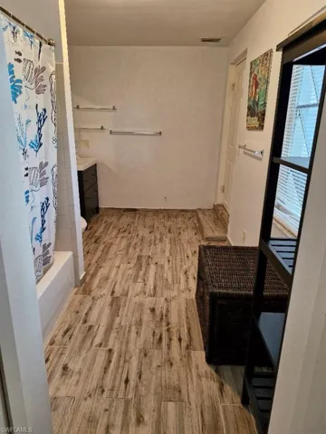 Bathroom with wood finished floors, shower / bath combo with shower curtain, vanity, and visible vents