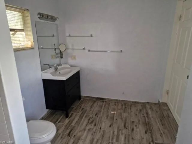 Bathroom featuring vanity, toilet, and wood finished floors