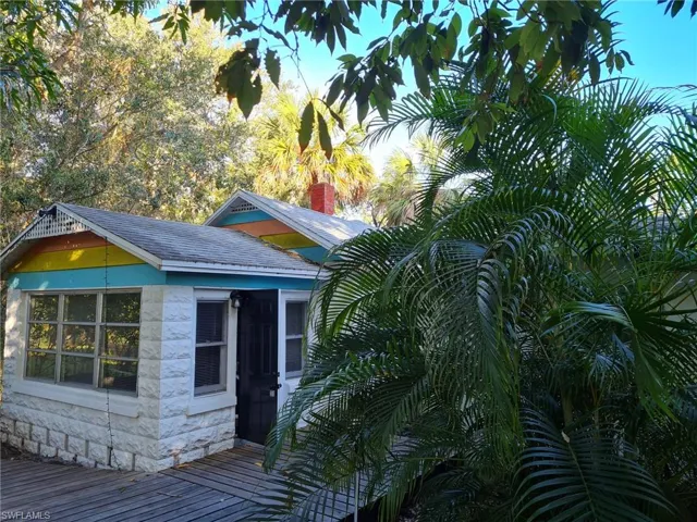 View of side of home featuring stone siding, roof with shingles, a chimney, and a wooden deck