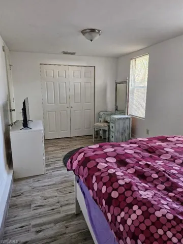 Bedroom with light wood-style floors, visible vents, and a closet