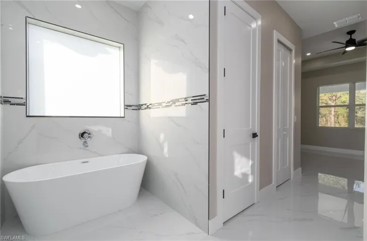 Bathroom featuring ceiling fan, tile walls, and a washtub