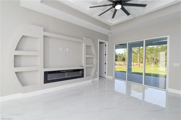 Unfurnished living room with a raised ceiling, built in shelves, and ceiling fan