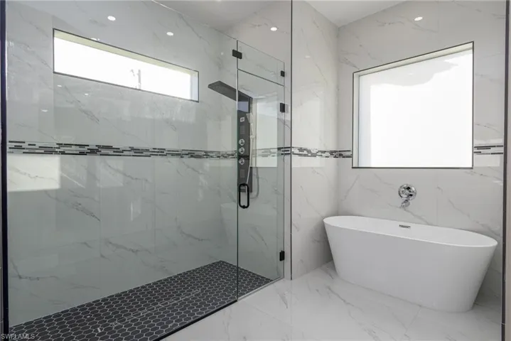 Bathroom featuring independent shower and bath and tile walls
