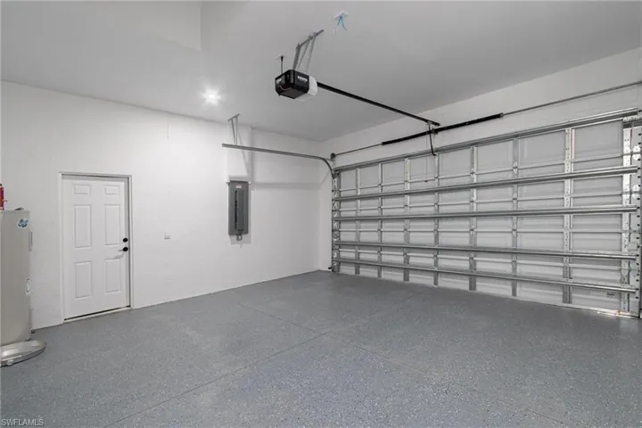 Garage featuring a garage door opener, electric panel, and electric water heater