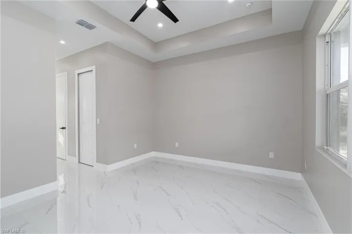Unfurnished room with a raised ceiling and ceiling fan