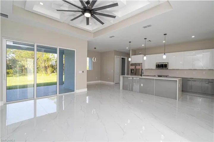 Kitchen with appliances with stainless steel finishes, a spacious island, white cabinetry, a tray ceiling, and pendant lighting