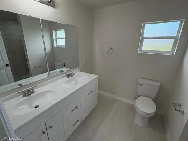 Bathroom featuring plenty of natural light, toilet, walk in shower, and vanity