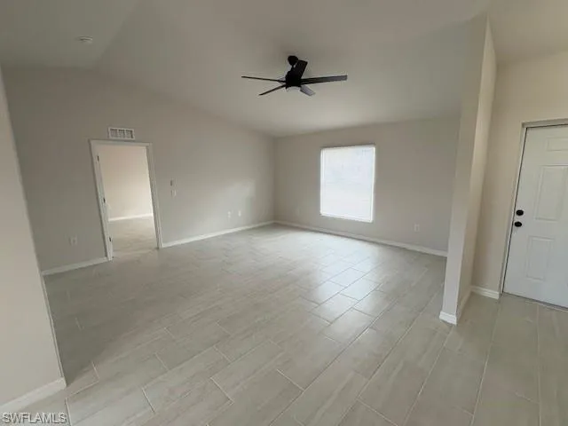 Empty room with light wood-type flooring, vaulted ceiling, and ceiling fan