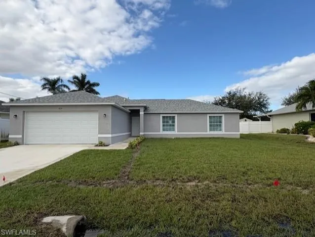 Single story home featuring a garage and a front lawn