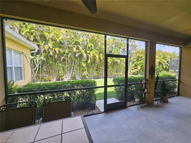 Screened lanai featuring a concrete floor, direct access to the yard, and surrounding lush tropical landscaping