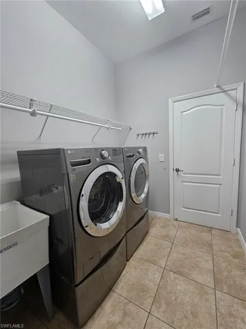 Utility room with light neutral wall paint and tile flooring