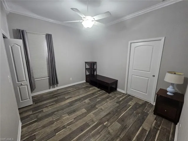 Room featuring wood-finish flooring, crown molding, and a ceiling fan